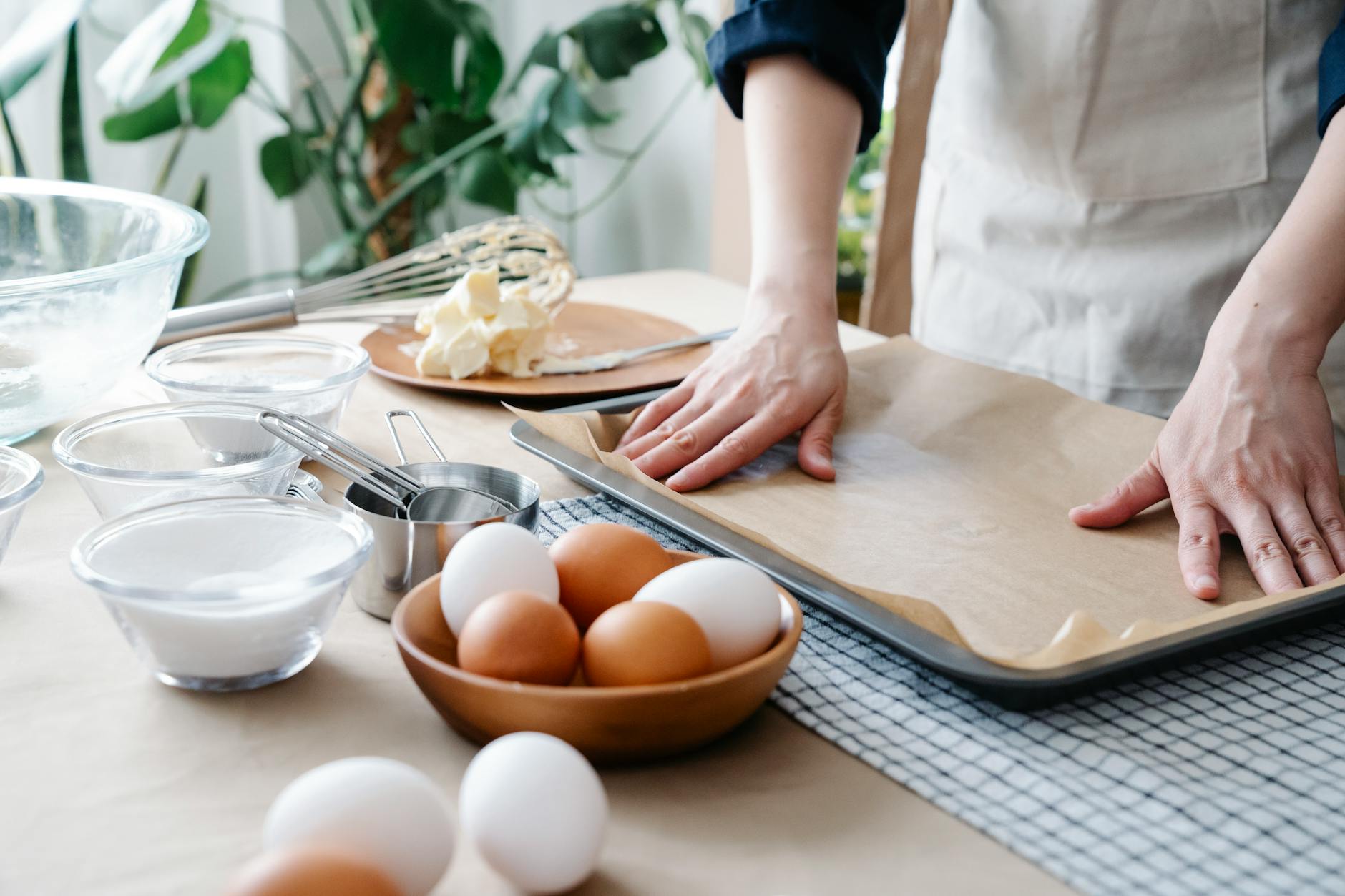 Hands preparing baking tray with ingredients ready for baking, including eggs and flour. (Photo by Felicity Tai on Pexels)